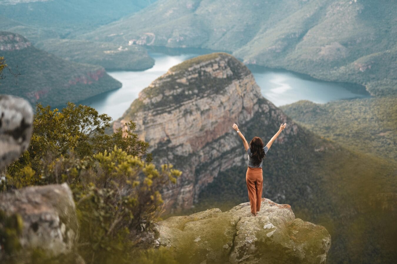 Woman with arms raised celebrating nature at Blyde River Canyon, South Africa.